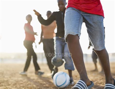 African boys playing soccer together in dirt field — low angle view ...