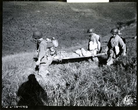 Wounded soldier being carried from battle zone during maneuvers near ...