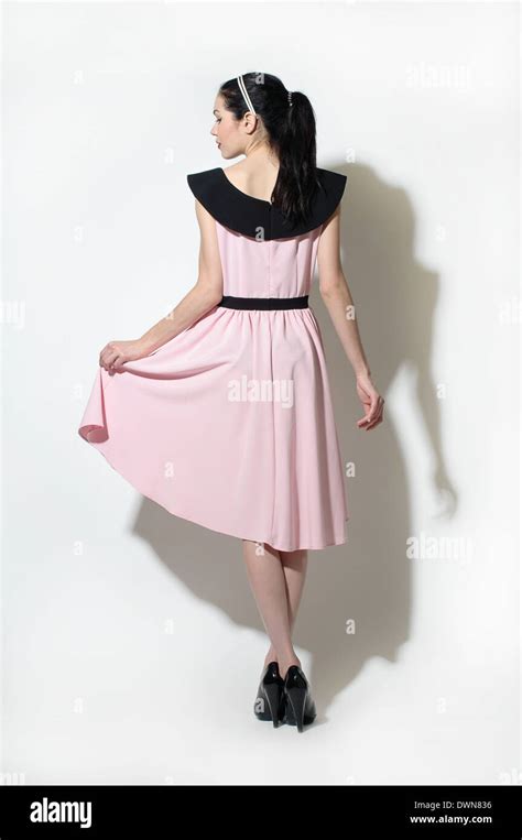 A Woman Dressed In A 50s Vintage Inspired Dress Holding Up Her Skirt