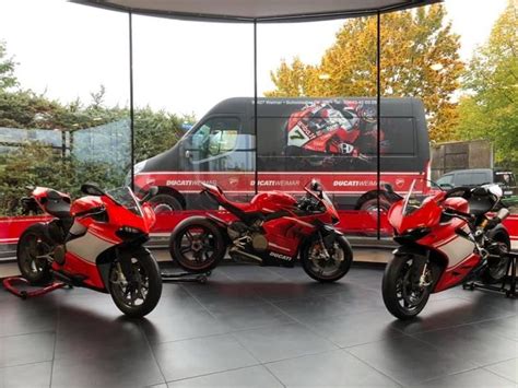 Three Red Motorcycles Are Parked In Front Of A Van And Some Trees On