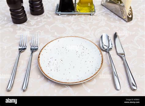 Table setting with plates, knife, fork and spoon, restaurant interior ...