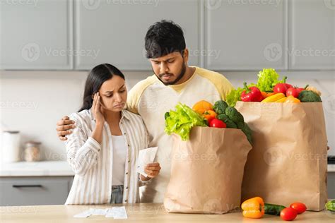 Shocked Spouses With Paper Bags With Food Checking Grocery Bill