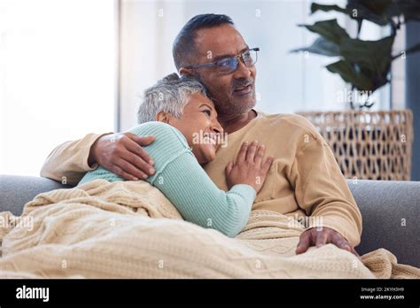 Senior Couple Hug And Love While On Living Room Couch Thinking About