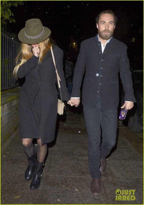 A Man And Woman Walking Down The Street Holding Hands