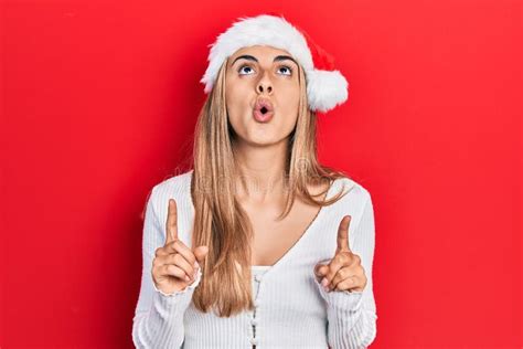 Beautiful Hispanic Woman Wearing Christmas Hat Amazed And Surprised