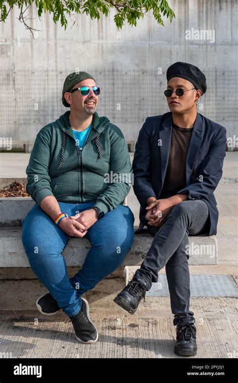 Gay Male Couple Talking Seriously While Sitting On A Bench Outdoors Stock Photo Alamy