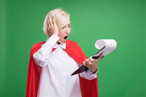 Femme super héros blonde d âge moyen en cape rouge tenant et regardant le presse papiers mettant