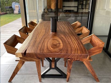 A Wooden Table With Six Chairs And A Vase Sitting On It S End In Front