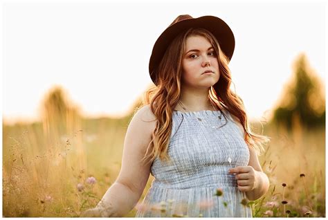 A Woman Standing In A Field Wearing A Hat