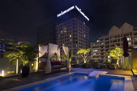 an outdoor swimming pool at night with buildings in the background