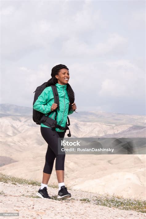 Happy African Woman Hiking Outdoors In Desert With Bag Stock Photo