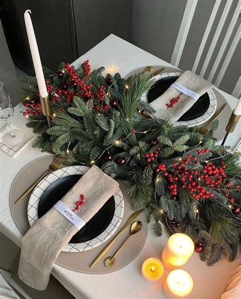 The Table Is Set For Christmas Dinner With Candles And Greenery On It