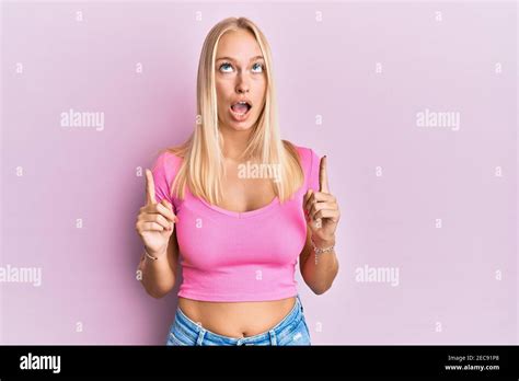 Junge blonde Mädchen tragen Casual Kleidung erstaunt und überrascht suchen und zeigen mit