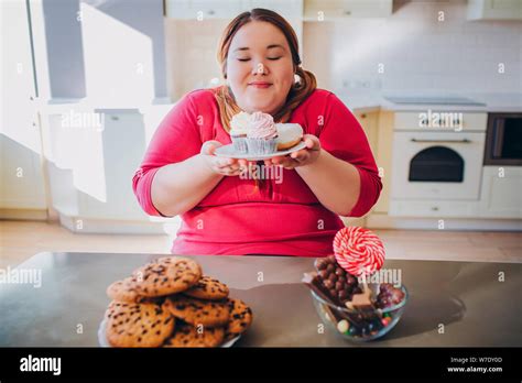 Fat Young Woman In Kitchen Sitting And Eating Sweet Food Plus Size