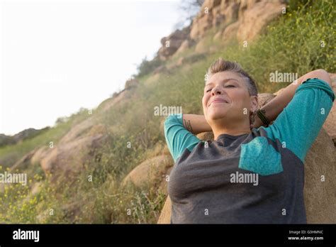 Woman Leaning Against Rock Eyes Closed Hands Behind Head Stock Photo