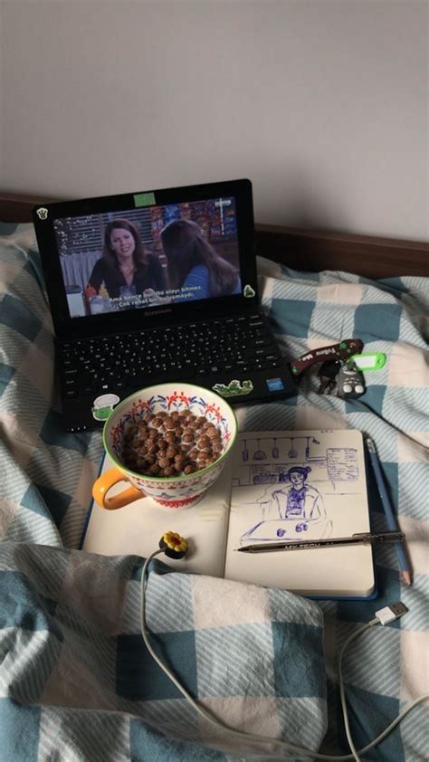 An Open Laptop Computer Sitting On Top Of A Bed Next To A Bowl Of Cereal