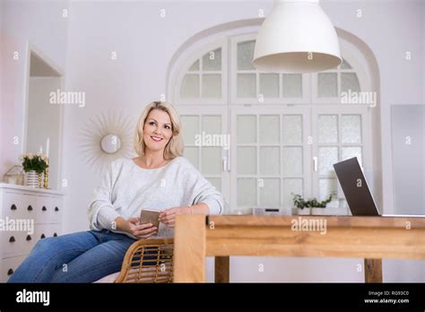 Portrait Smiling Blond Mature Woman Smartphone Laptop Home Hi Res Stock Photography And Images