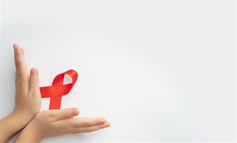 Aid는 흰색 배경에 어린이 손에 빨간 리본 Hiv Aids 및 암에 대한 투쟁의 상징입니다 도움이 필요한 사람들을 돕는 개념