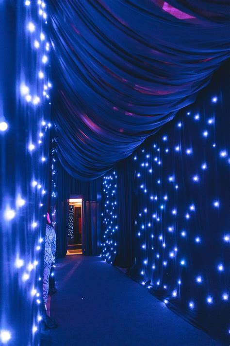 A Man Standing In Front Of A Blue Curtain Covered Tunnel With Lights On