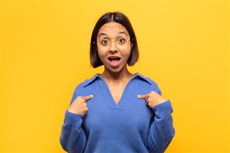 Joven latina que se siente feliz sorprendida y orgullosa señalando a sí misma con una mirada