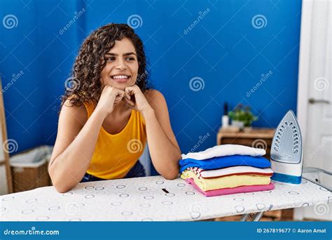 Young Latin Woman Smiling Confident Leaning On Ironing Table At Laundry