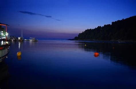 Boats Are Docked On The Water At Night With Blue Sky And Clouds In The