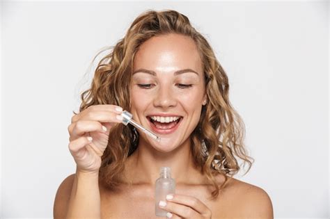 Premium Photo Happy Half Naked Woman Smiling And Using Facial Serum Isolated Over White Wall