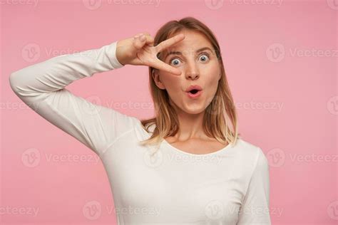 Portrait Of Attractive Blue Eyed Blonde Lady Posing Over Pink Background With Wide Eyes Opened