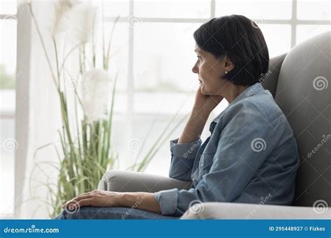 Pensive Mature Woman Sits On Armchair Staring Into Distance Stock Image