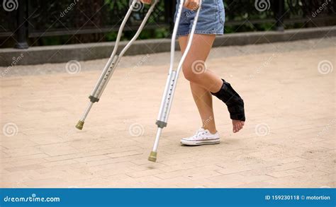 Patient With Injured Ankle Walking On Crutches Outdoors Leg Strain