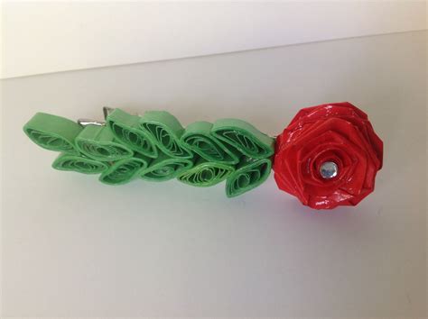 Two Red And Green Flower Clips On A White Surface