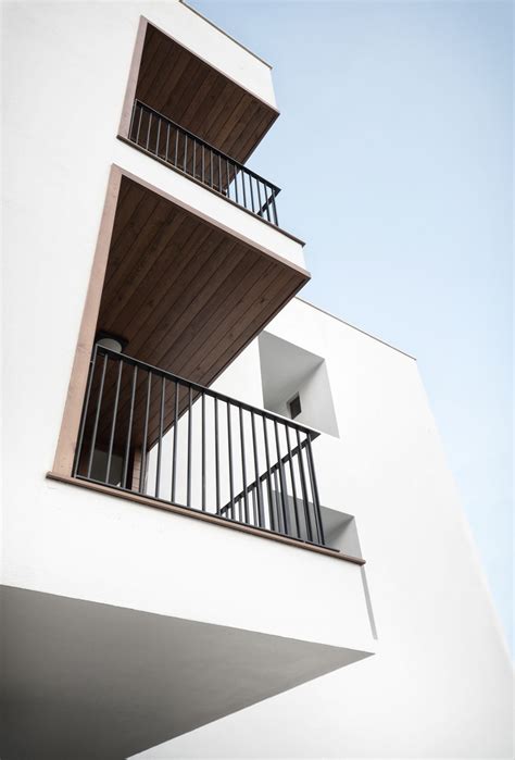 Two Balconies On The Side Of A White Building With Wooden Balconies