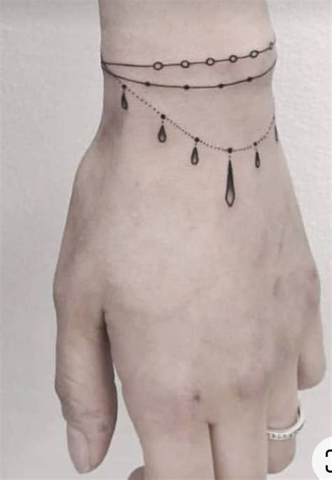 A Person S Hand With A Chain On It And Some Dangling Beads Around The Wrist