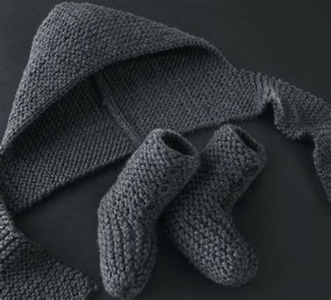 Two Knitted Mittens One In Grey And The Other In Gray On A Black Surface