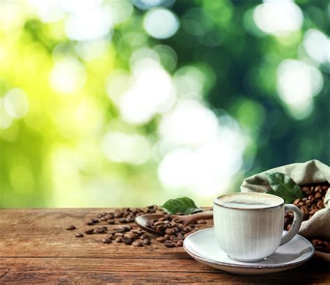 Premium Photo Cup Of Aromatic Hot Coffee And Beans On Wooden Table