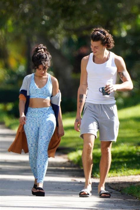 A Man And Woman Walking Down The Street Together Both Wearing Matching