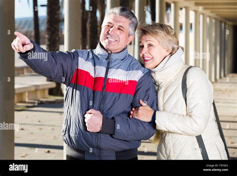 Mature Married Couple Walk And Husband Points To Wife To Something Interesting Stock Photo Alamy