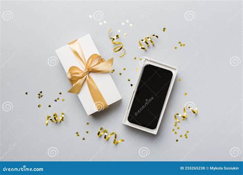 Opened T Box With Gold Ribbon And Smartphone On Color Background