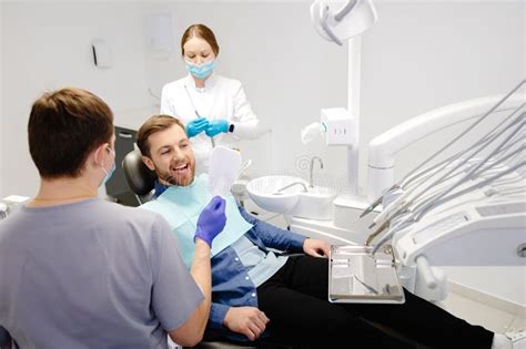 Handsome Male Patient Looking At His Beautiful Smile Sitting At The