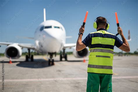 Welcome Home Back View Of Aviation Marshaller Directing Aircraft