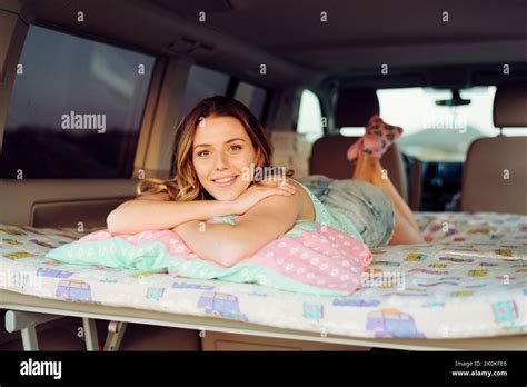 Blonde Cheerful Pretty Woman Lying On Folding Bed Inside A Minivan And
