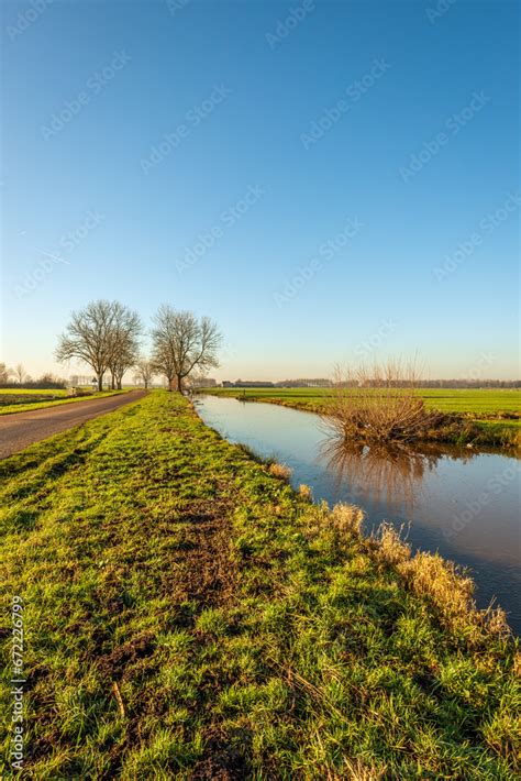 Polder Landscape With A Ditch Covered With A Thin Layer Of Ice The