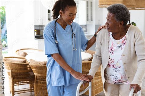 Smiling African American Female Doctor Assisting Senior Woman Walking