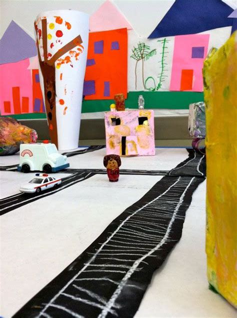 There Is A Train Track With Cars On It And Paper Houses In The Back Ground