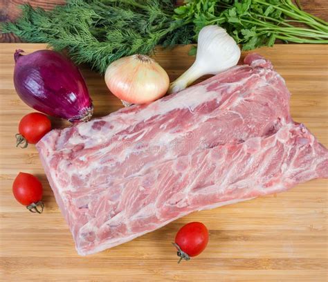 Uncooked Pork Loin Among Vegetables On Cutting Board Top View Stock