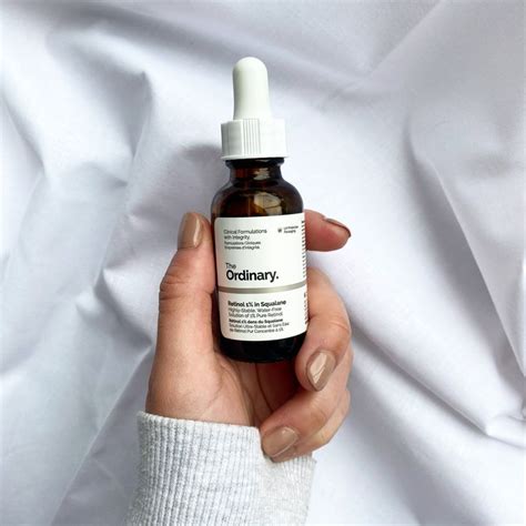 The Ordinary 1% Retinol in Squalane held with a hand with painted nails ...