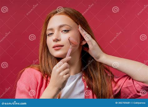 Young Woman With Rose Quartz Stone Roller On Pink Background Facial