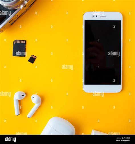 Smartphone and wireless headphones. Mobile phone and accessories on yellow background Stock ...