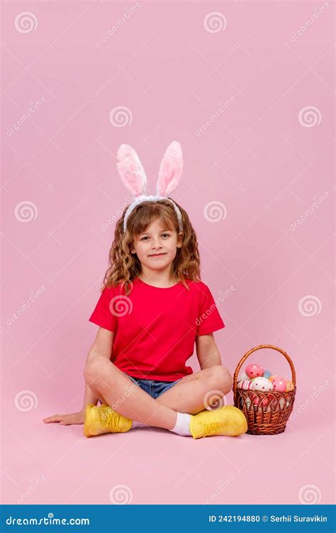 Girl In Easter Bunny Ears Sitting On The Floor Near Basket With Easter