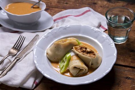 A White Plate Topped With Dumplings Next To A Cup Of Soup And Silverware